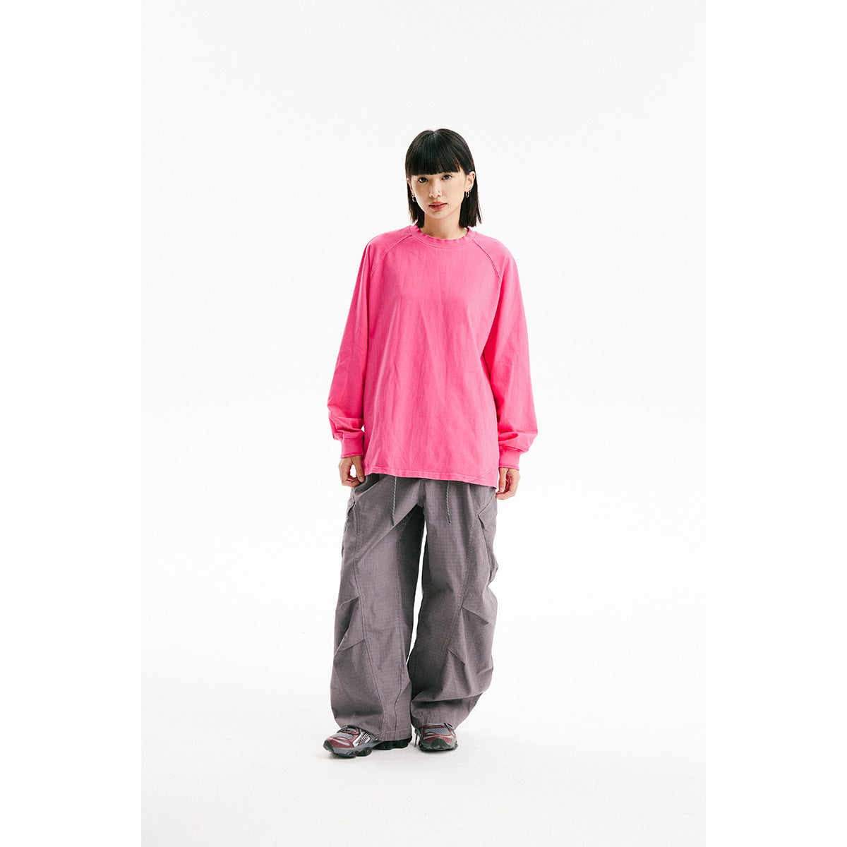 Model wearing an oversized bright pink long-sleeve shirt with gray wide-leg cargo pants.