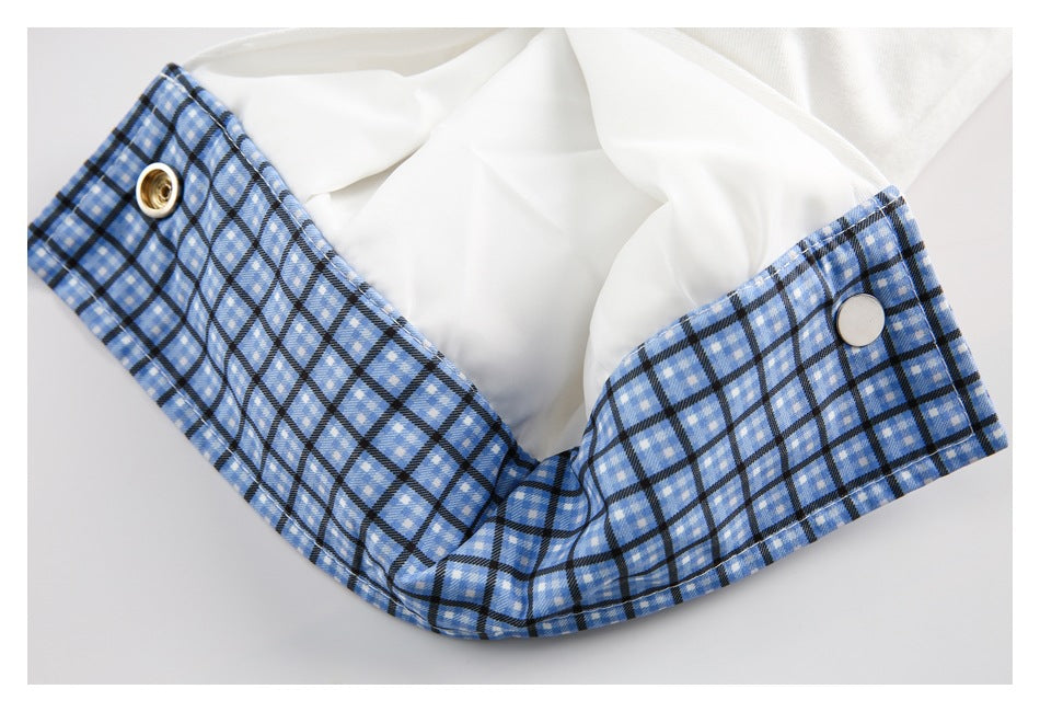Close-up of blue plaid fabric around a white garment opening, with two metal fasteners.