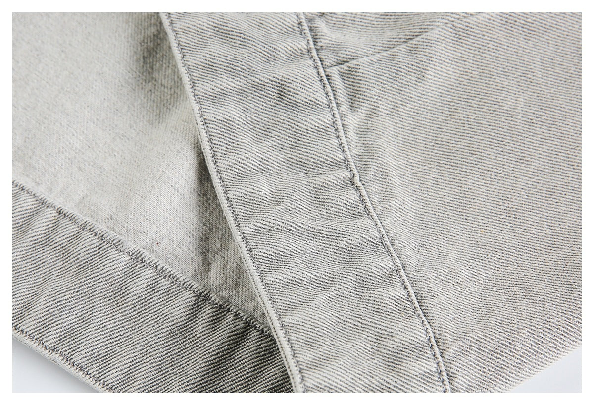Close-up of light gray denim garment showing overlapping panels and stitched seams.