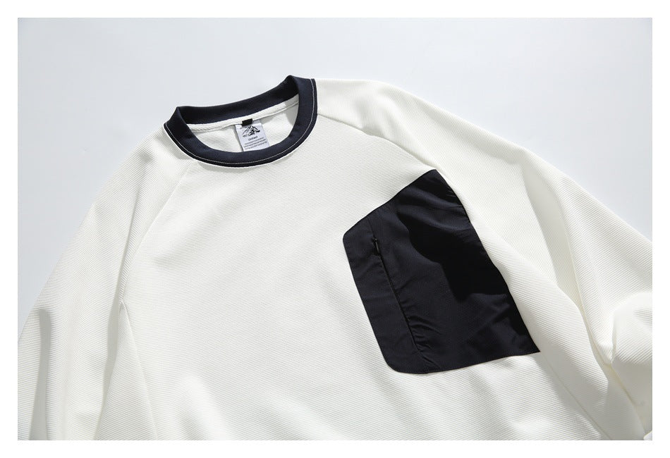 Close front view of an off-white long-sleeve crewneck with a dark navy collar and large navy chest pocket.