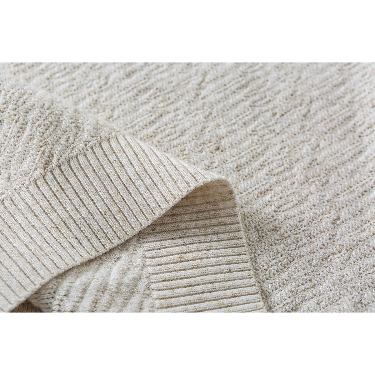 Close-up of the textured cream knit and ribbed hem of a pullover.