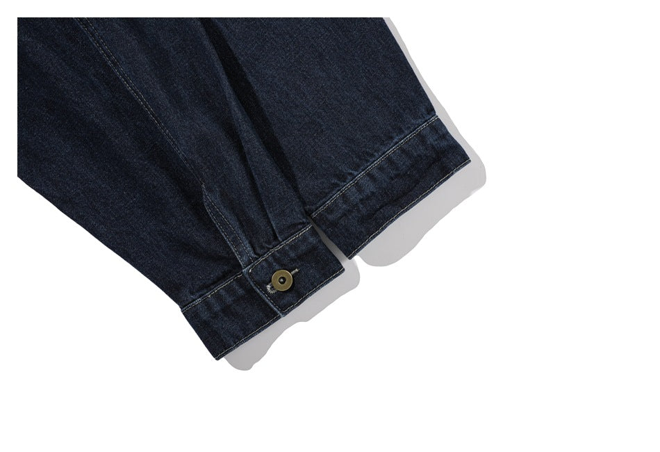 Close-up of dark indigo denim jacket sleeves with stitched cuffs and a brass-tone button.