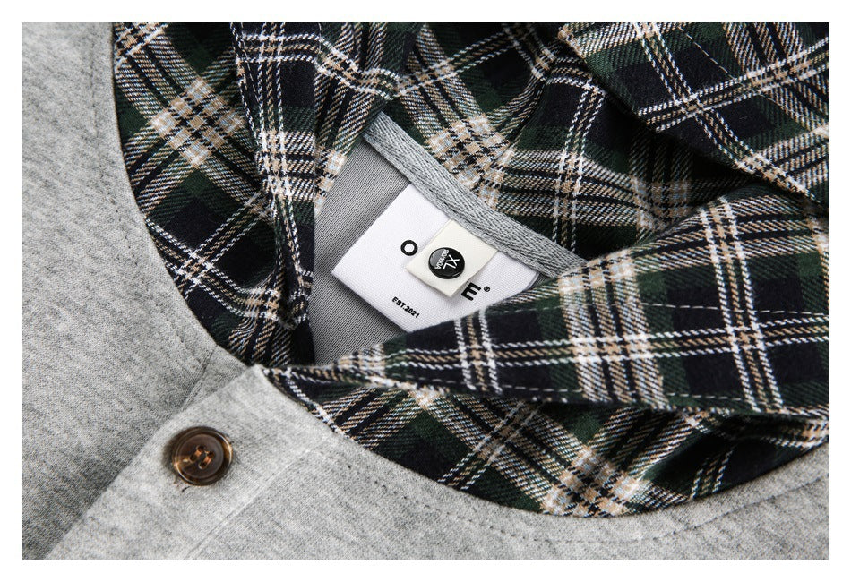 Close-up of the plaid neckline and a small garment label on a gray top.