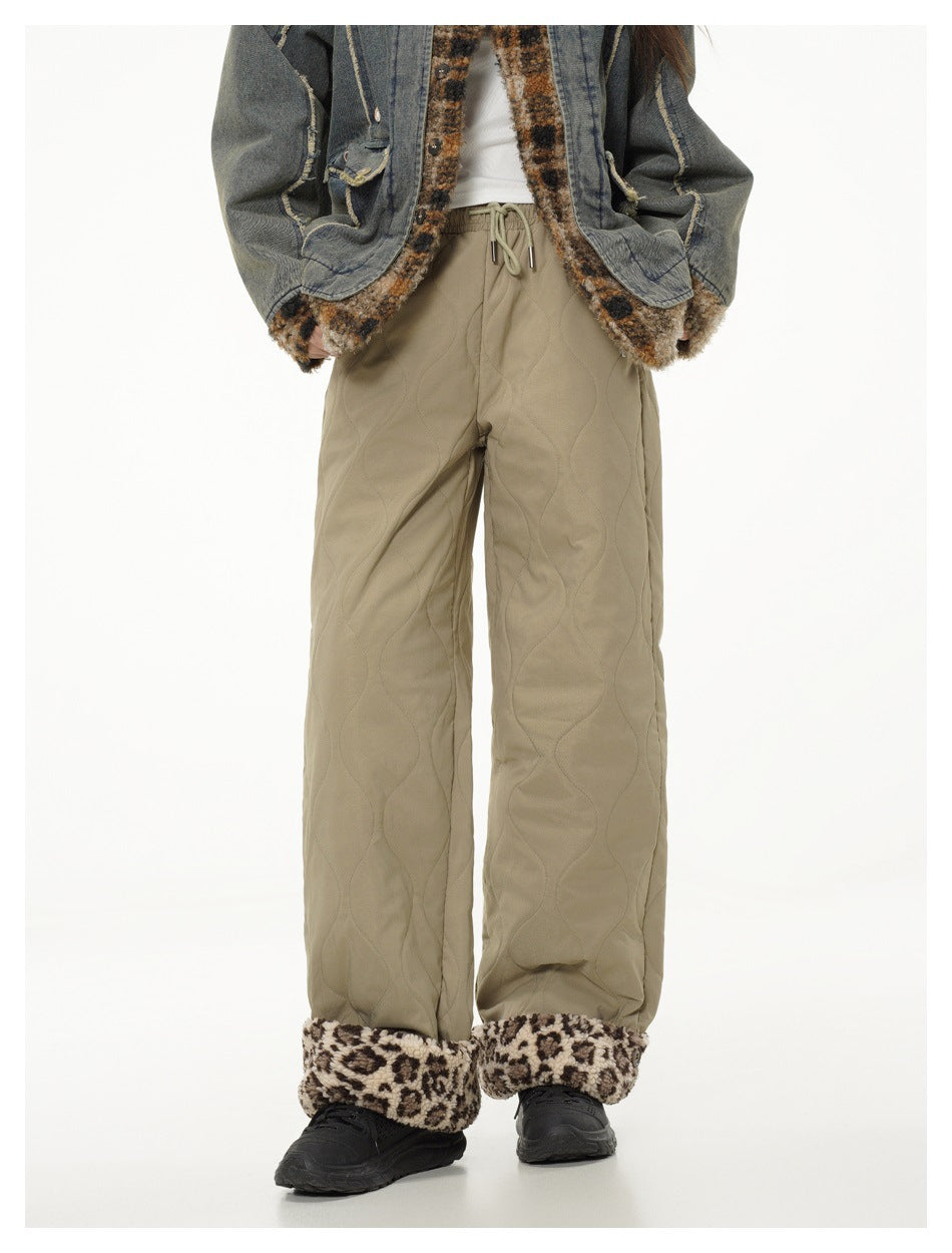 Model wearing green quilted wide-leg pants with leopard fleece-like cuffs, a denim jacket and black sneakers, front view