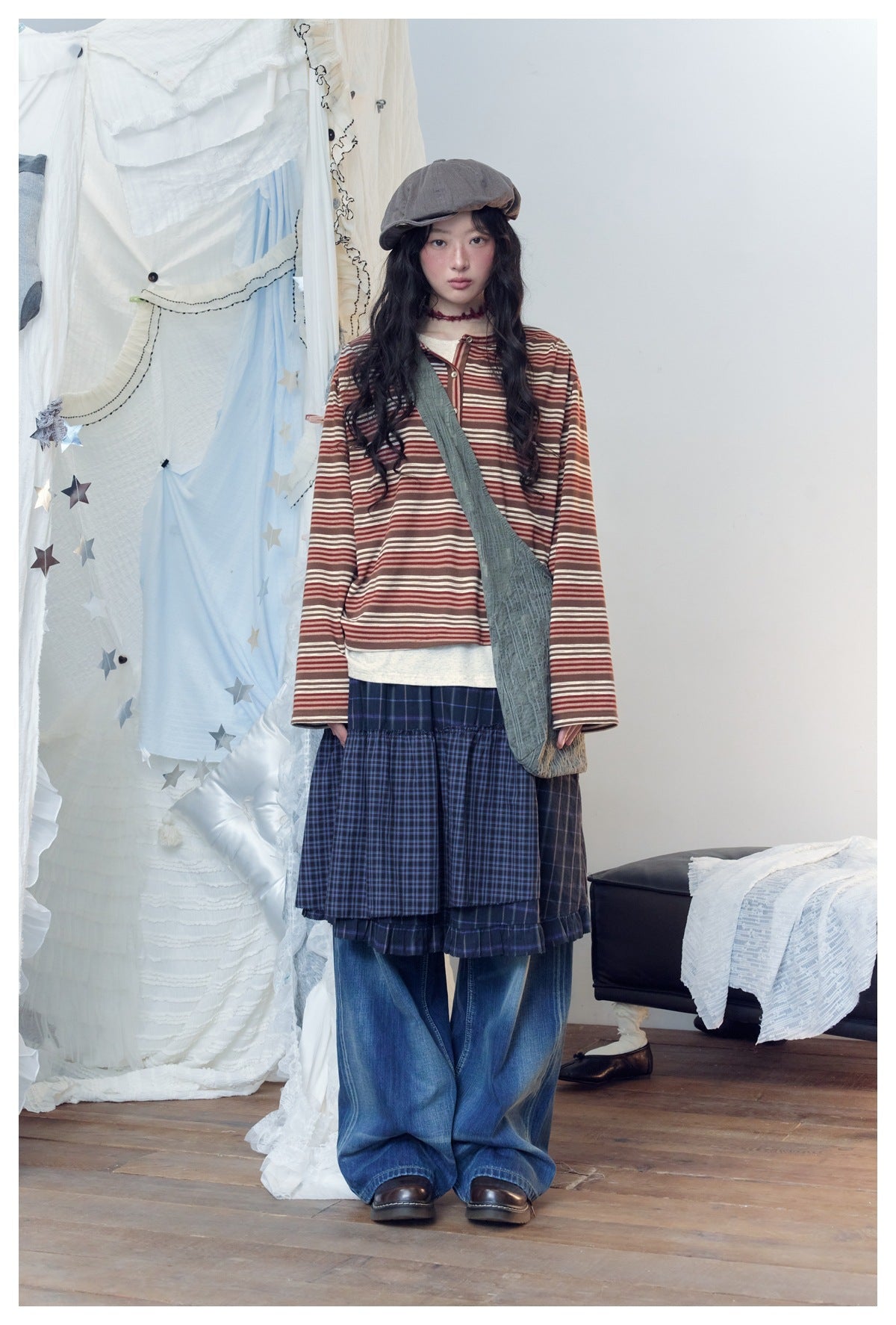 Full-length model in a brown and rust striped long-sleeve top, navy plaid tiered skirt and loose blue jeans.