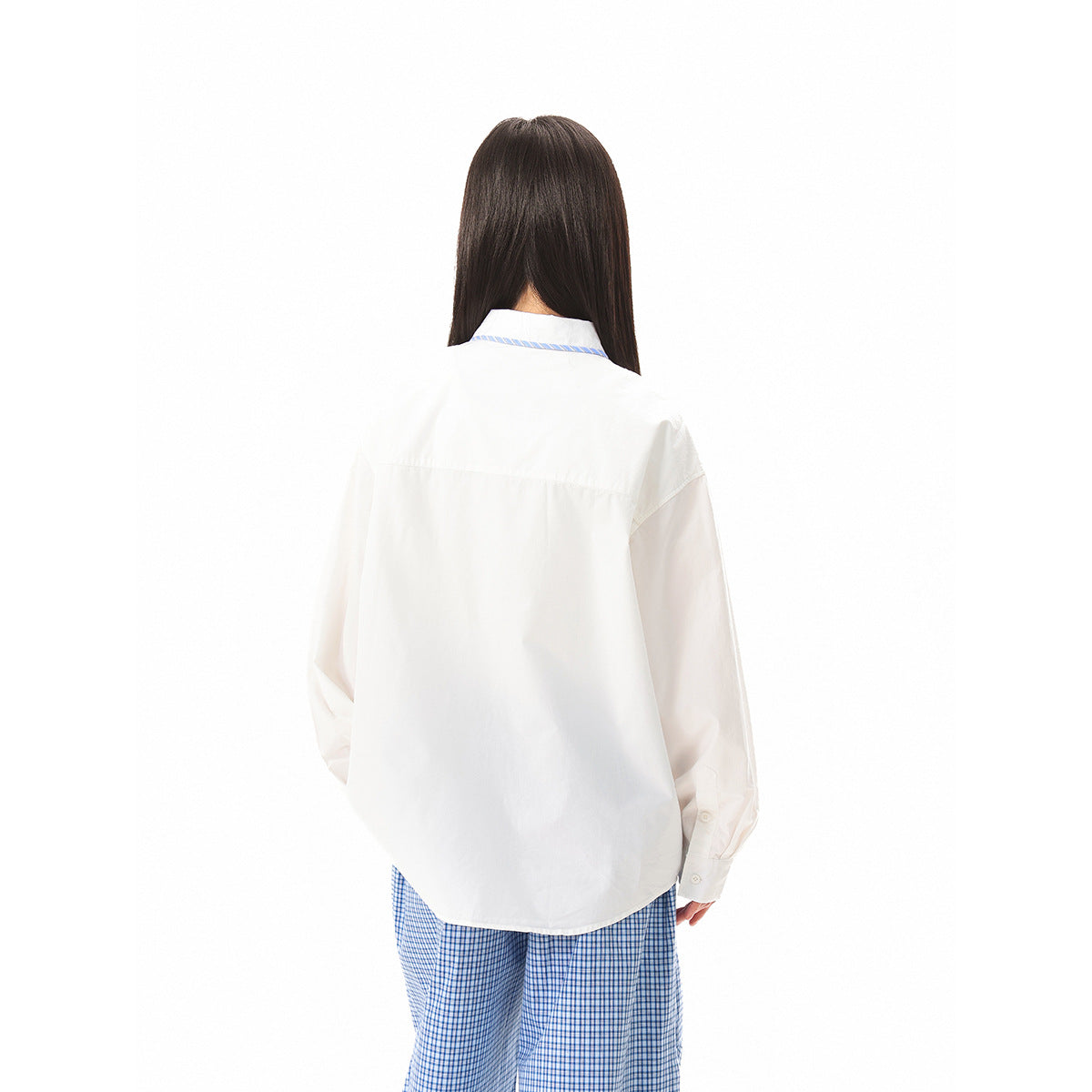 Back view of a model wearing a loose white shirt with blue collar trim and blue checked trousers.