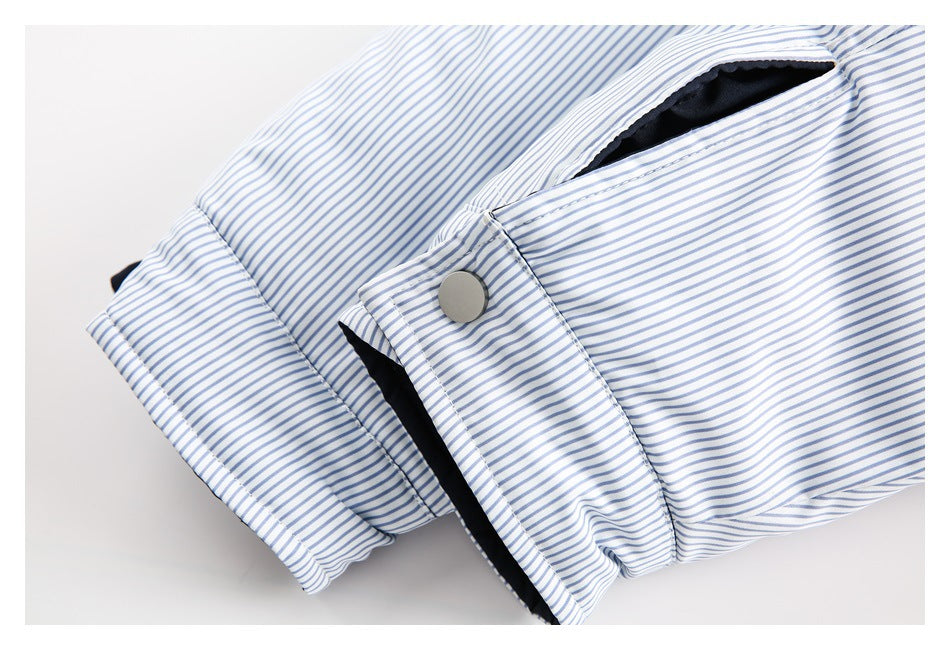 Close-up of a blue-and-white striped garment showing a cuff, a gray snap, and a pocket opening with dark lining.