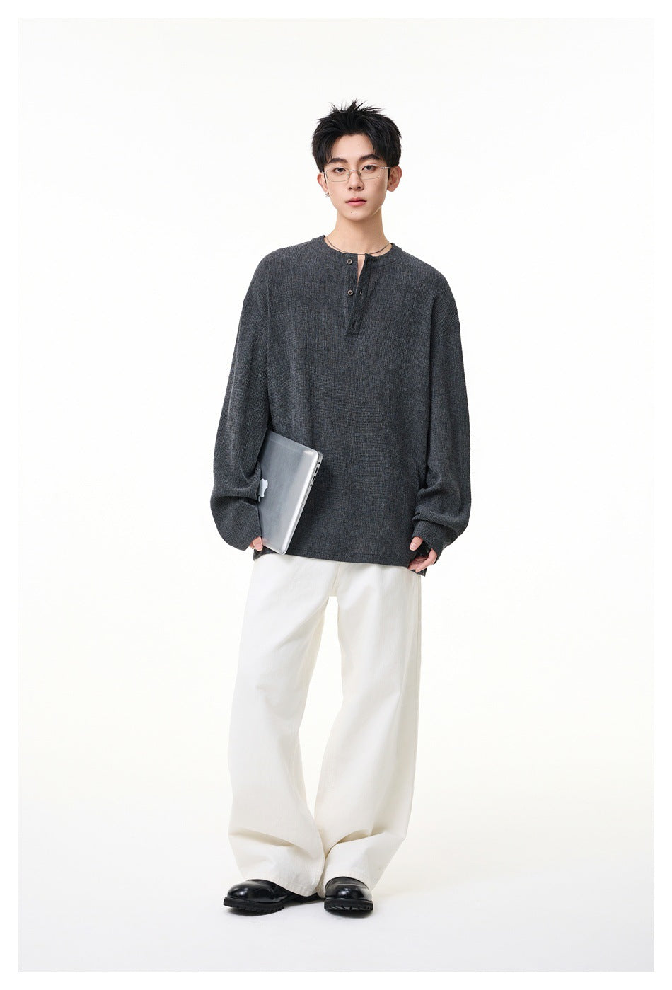 Full-length model wearing a dark charcoal oversized henley, white wide-leg trousers, and black shoes.