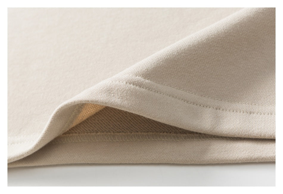 Close-up of a beige garment hem showing the stitched edge and overlocked underside.