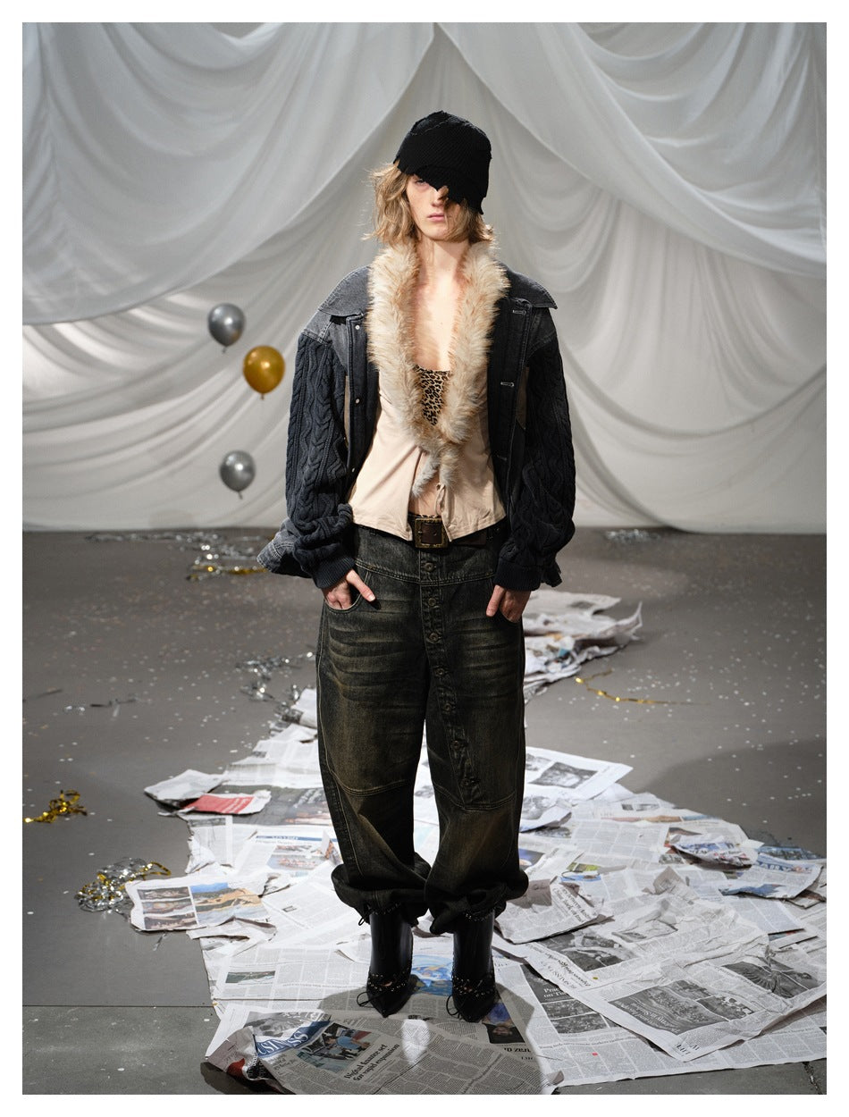 Model wearing an open charcoal jacket with black cable-knit sleeves and a cream fur collar, with dark jeans and a black knit