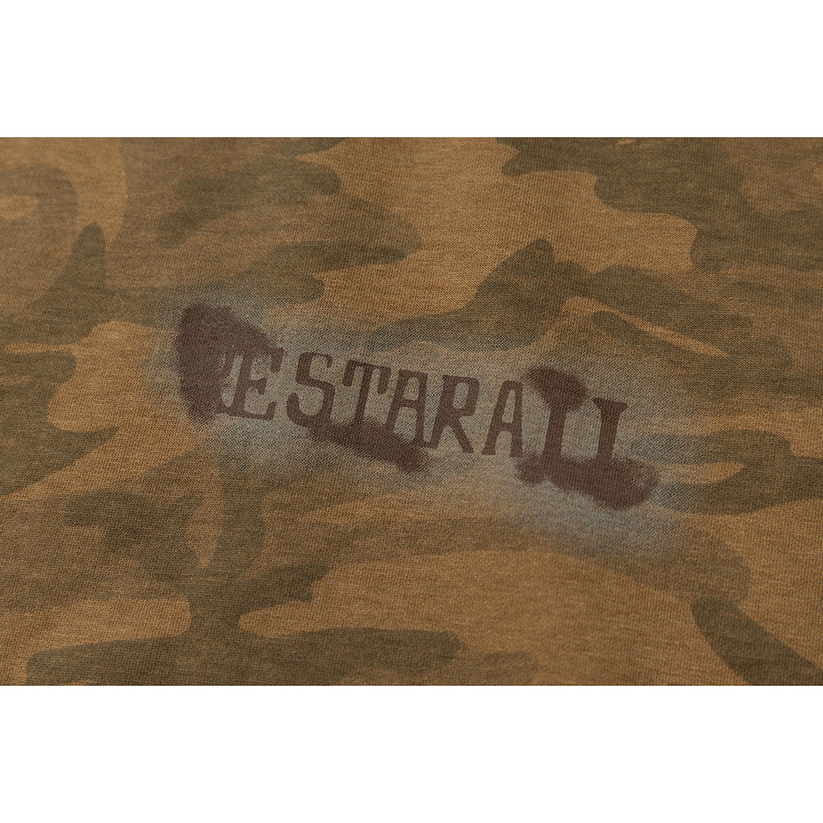 Close-up of a dark English wordmark printed on brown camouflage fabric.