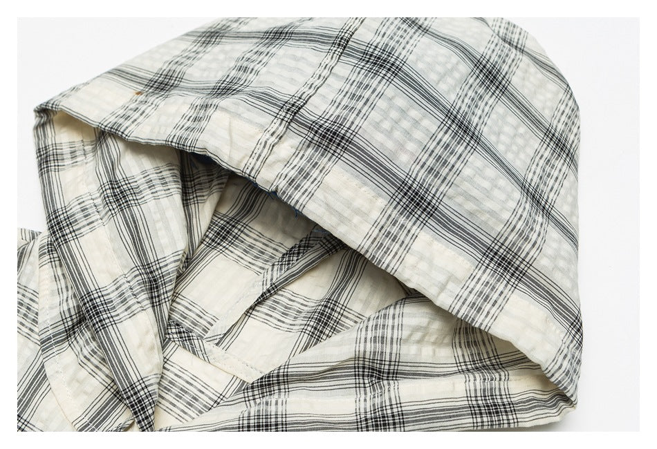 Close-up of a folded cream garment with a black plaid pattern.
