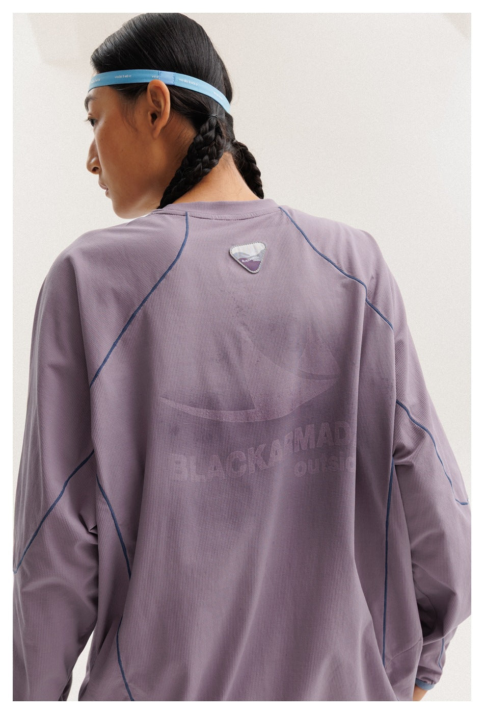 Close rear view of the lavender top, showing blue seam piping and a large tonal graphic across the back.