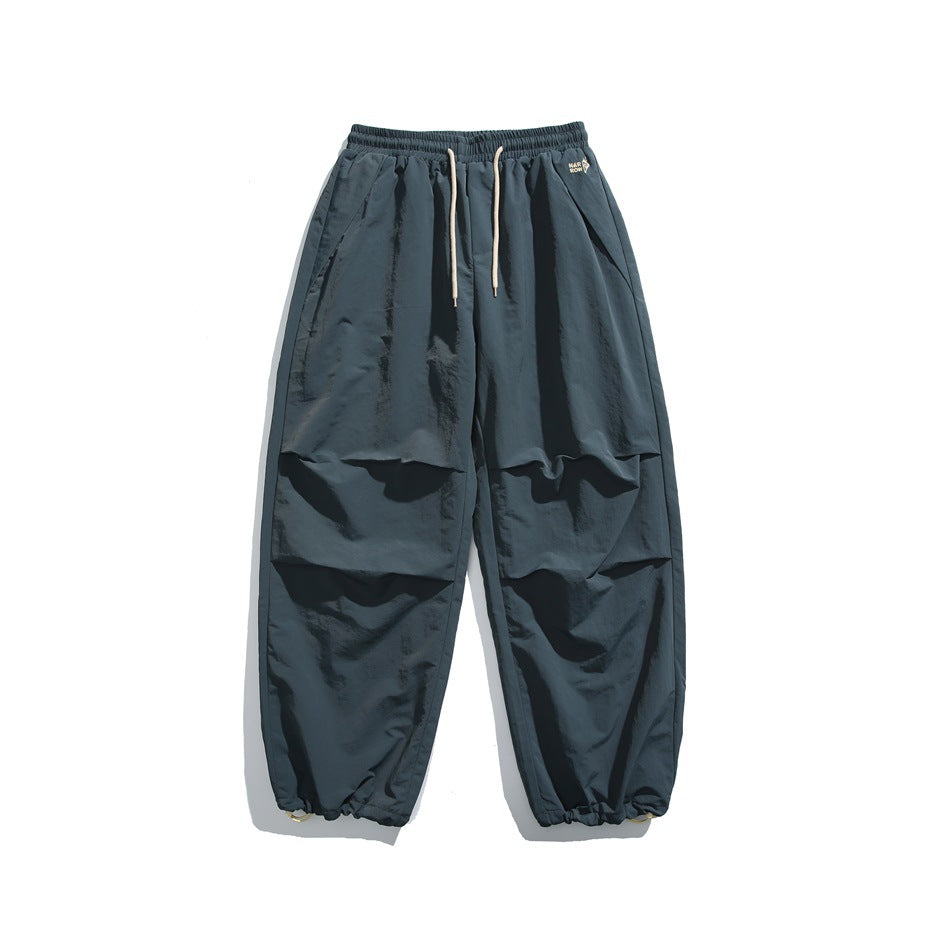 Navy-blue wide-leg drawstring pants with cream cords, pleated knees and drawcord hems, flat lay