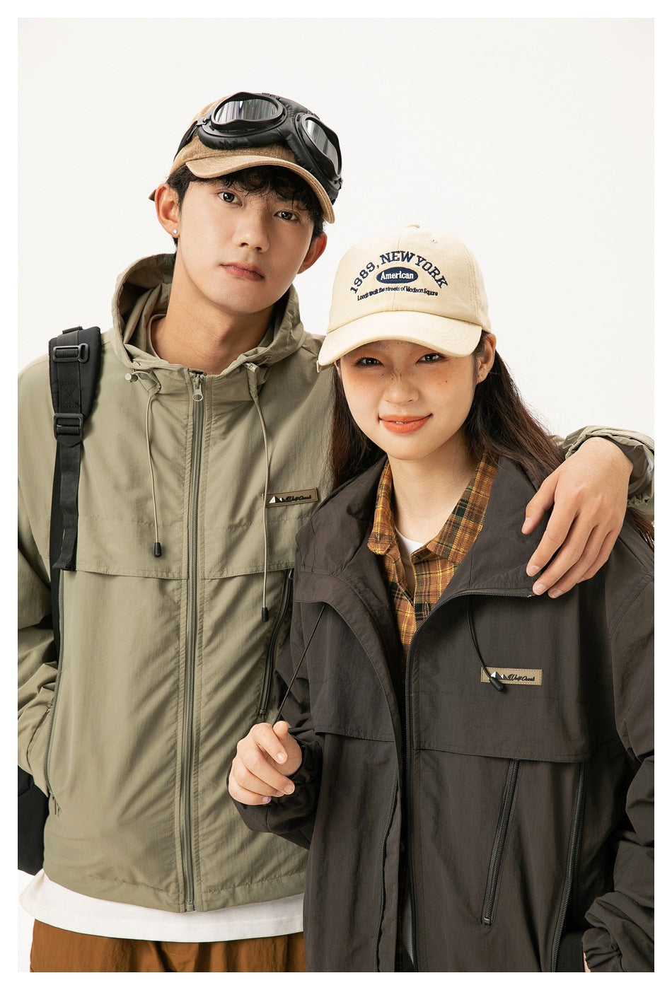Close view of two models wearing khaki and dark brown hooded jackets with front zippers and chest pockets.