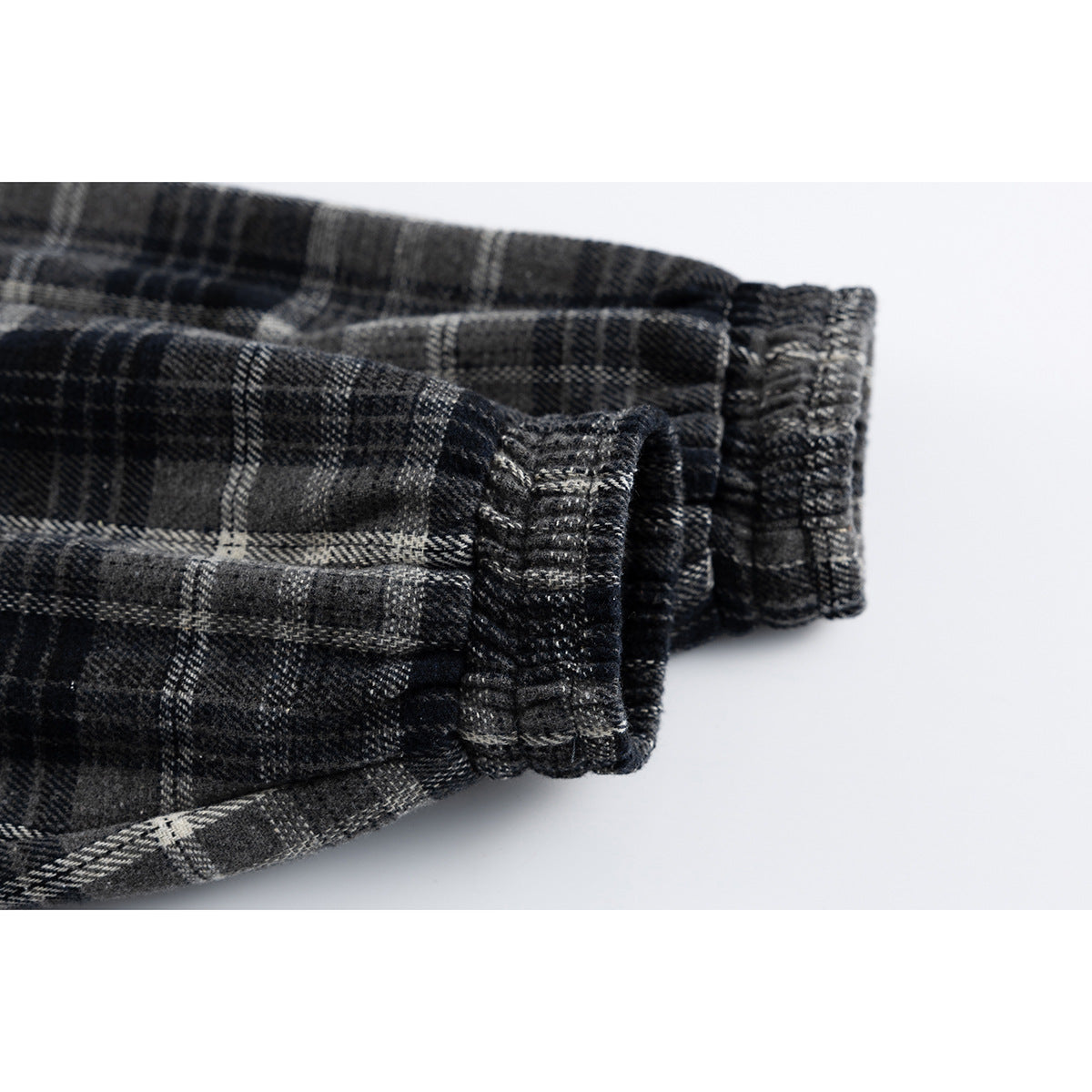 Close-up of the gathered cuff and sleeve of a charcoal and gray plaid jacket.