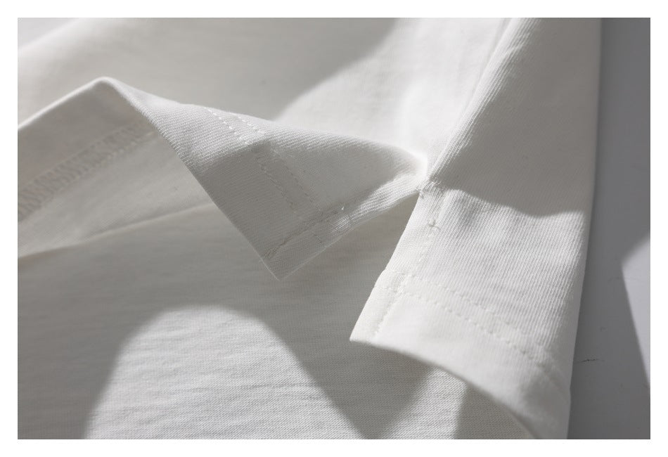 Close-up of the white T-shirt hem and stitching, showing the fabric edge turned back.