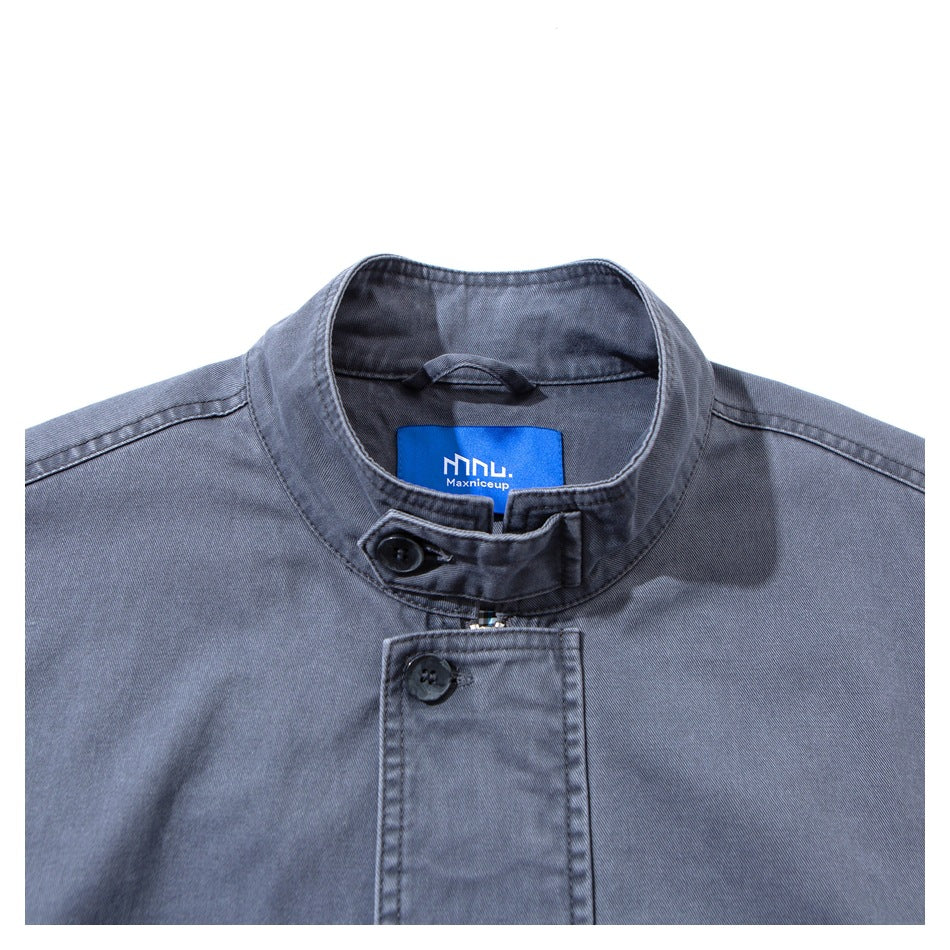 Close-up of the dusty blue jacket's stand collar, buttoned zipper flap, and blue neck label.