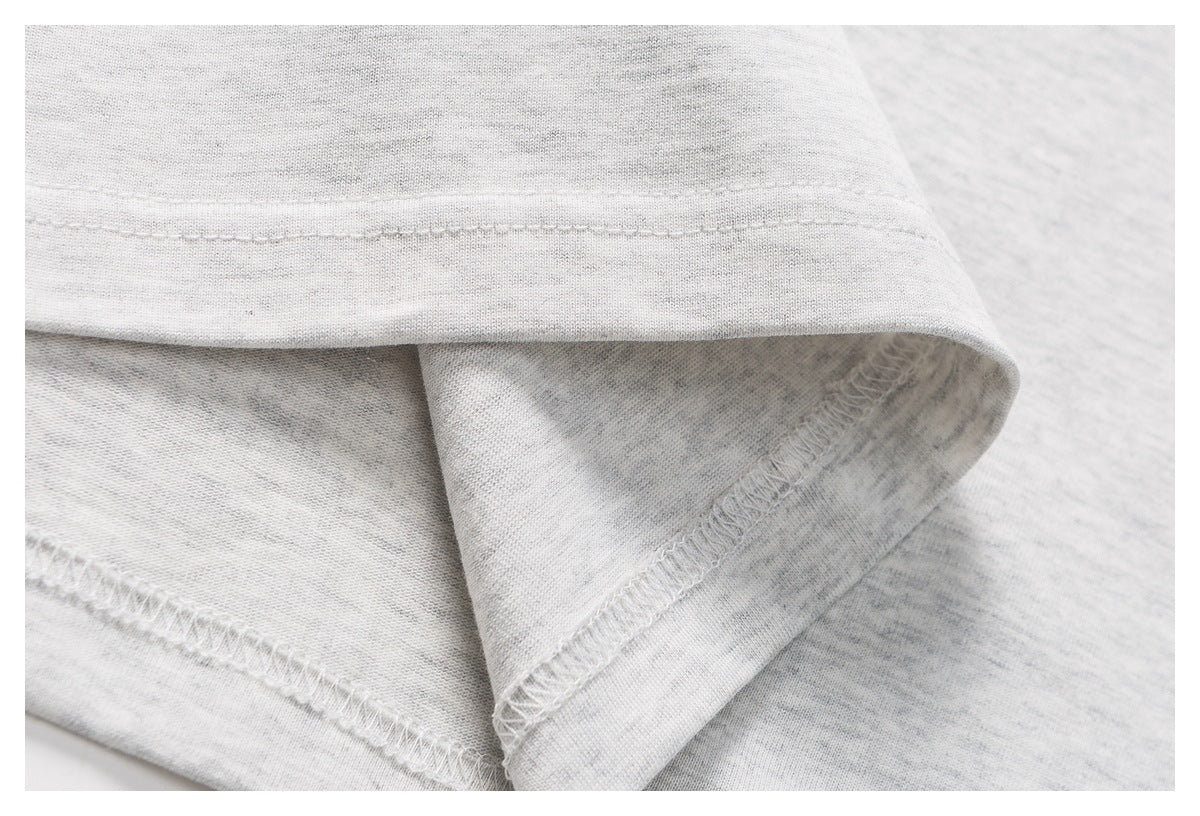 Close-up of the light gray shirt hem, showing the folded edge and interior overlock stitching.