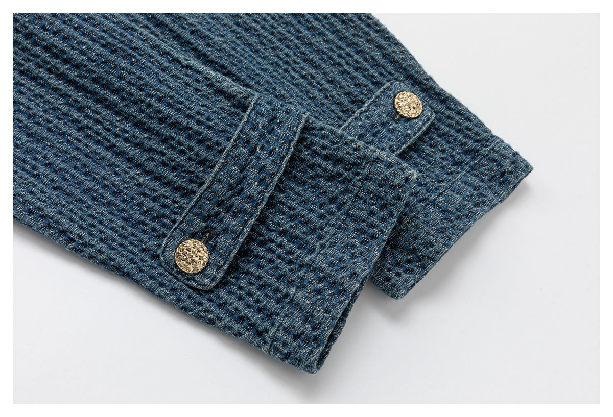 Close-up of a blue woven garment cuff with two ornate gold-tone buttons.