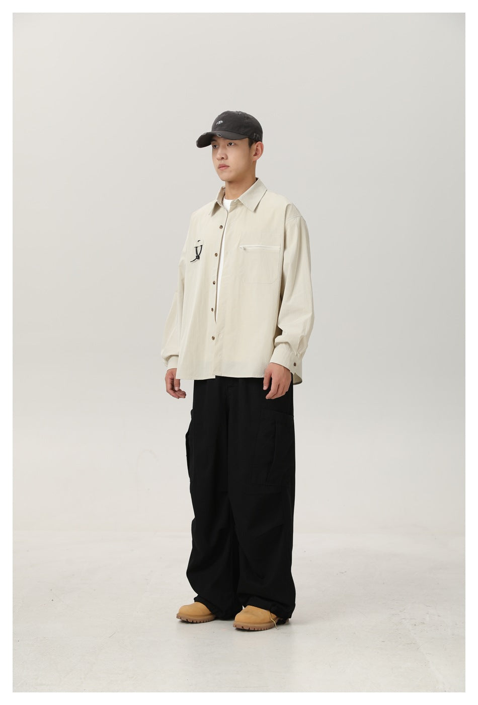 Full-length view of a model wearing an ivory button-up shirt with a zip chest pocket and black cargo pants.