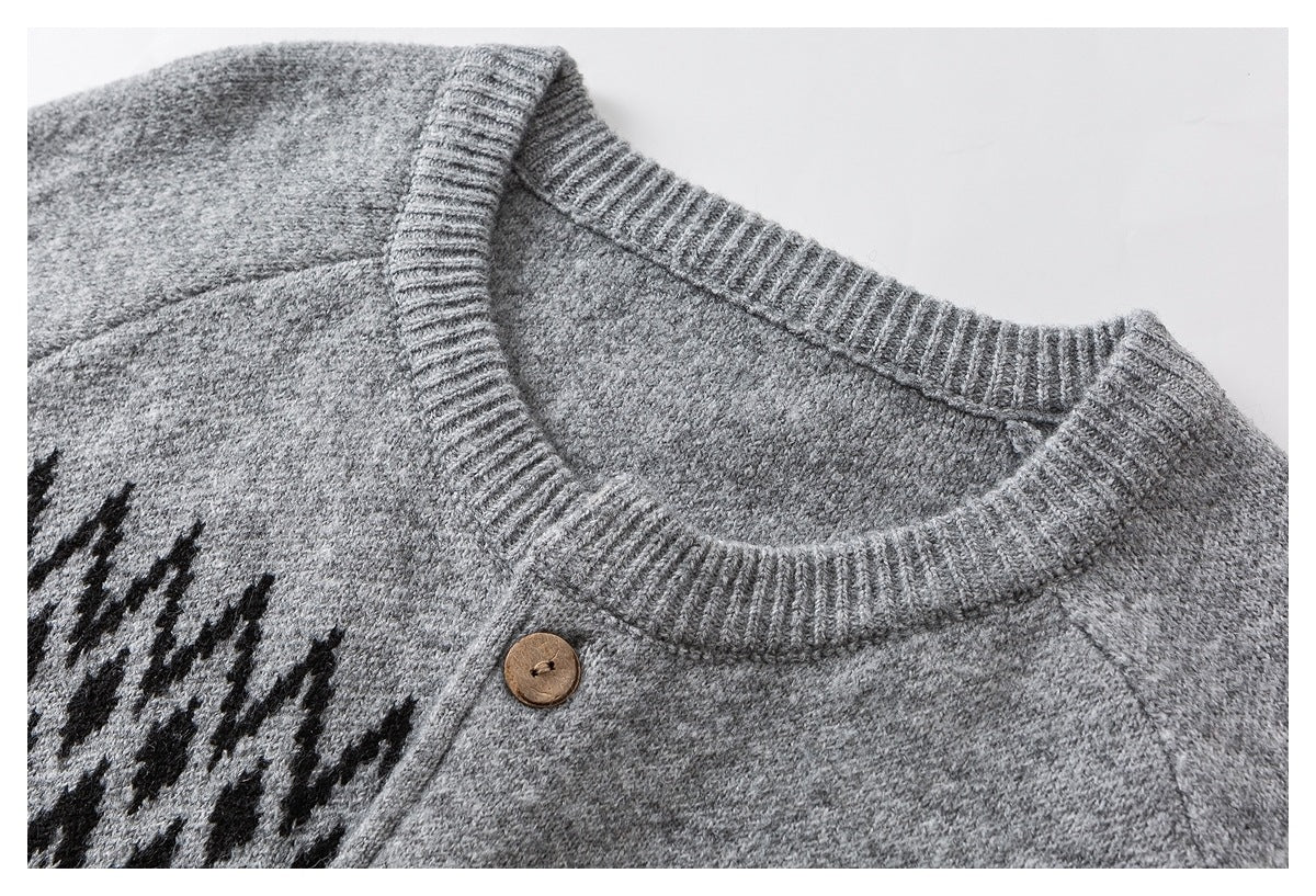 Close-up of a gray sweater's ribbed crew neck, raglan seam, brown button, and black patterned section.