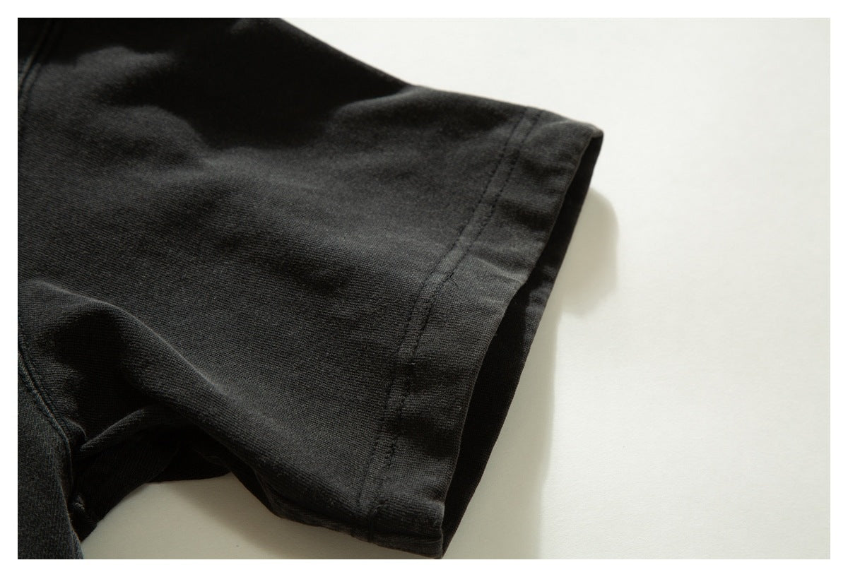Close-up of a black garment sleeve hem with visible stitching against a light background.