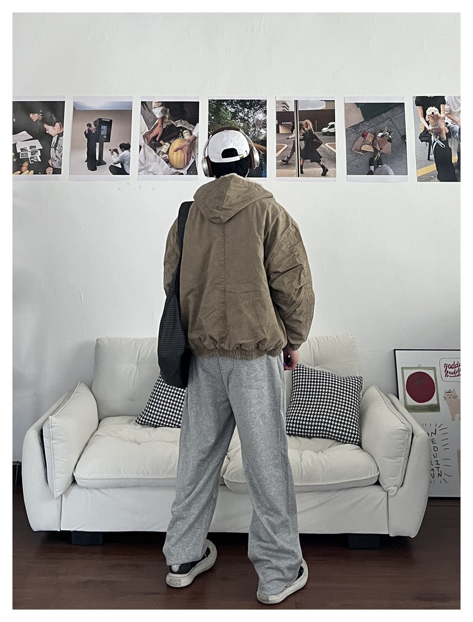 Person wearing an olive-brown hooded jacket, shown from the back with gray sweatpants.