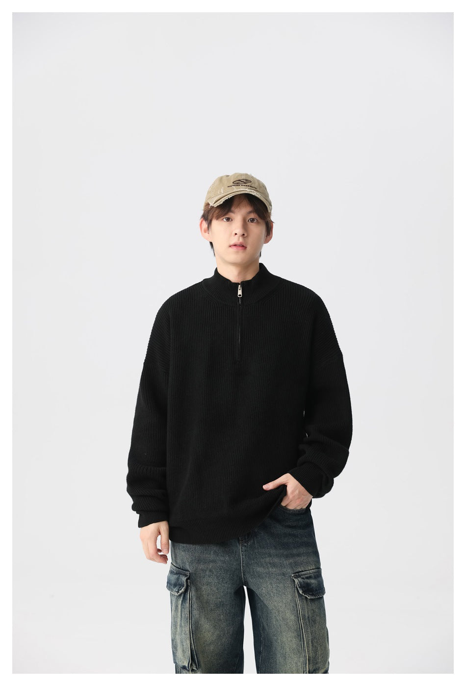 Model wearing a black ribbed quarter-zip sweater with a stand collar and loose cargo jeans.