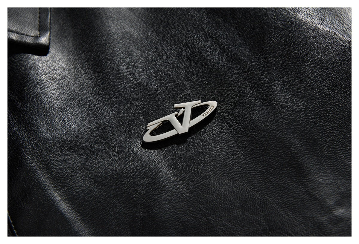 Close-up of a small silver decorative badge on the textured black jacket.