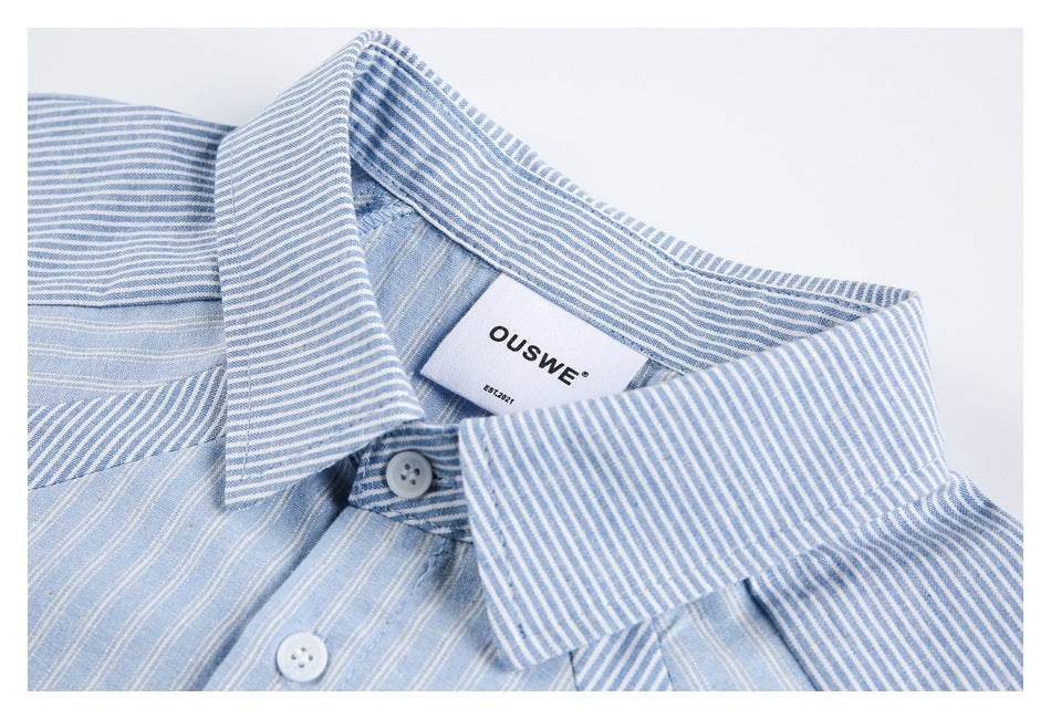 Close-up of the light blue striped shirt's collar, top button, and sewn-in label.