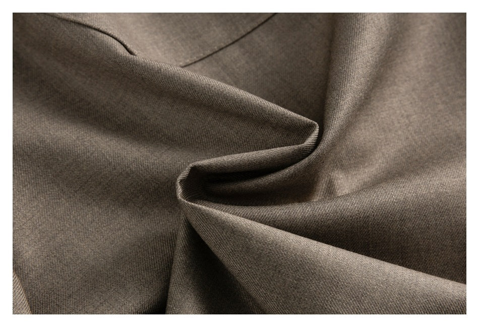Close-up of taupe-brown garment fabric arranged in soft folds.