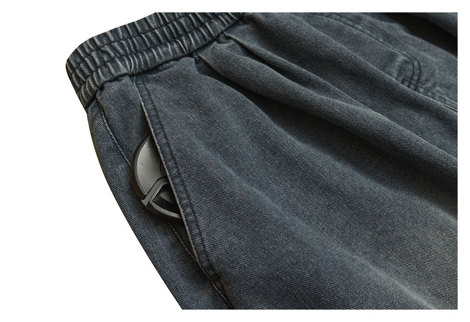 Close-up of a side pocket on dark gray denim pants, with a small gray object partly visible inside.