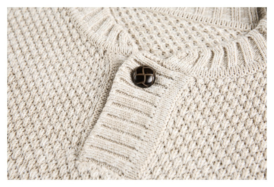 Close-up of a dark button and ribbed placket on a cream textured knit sweater.