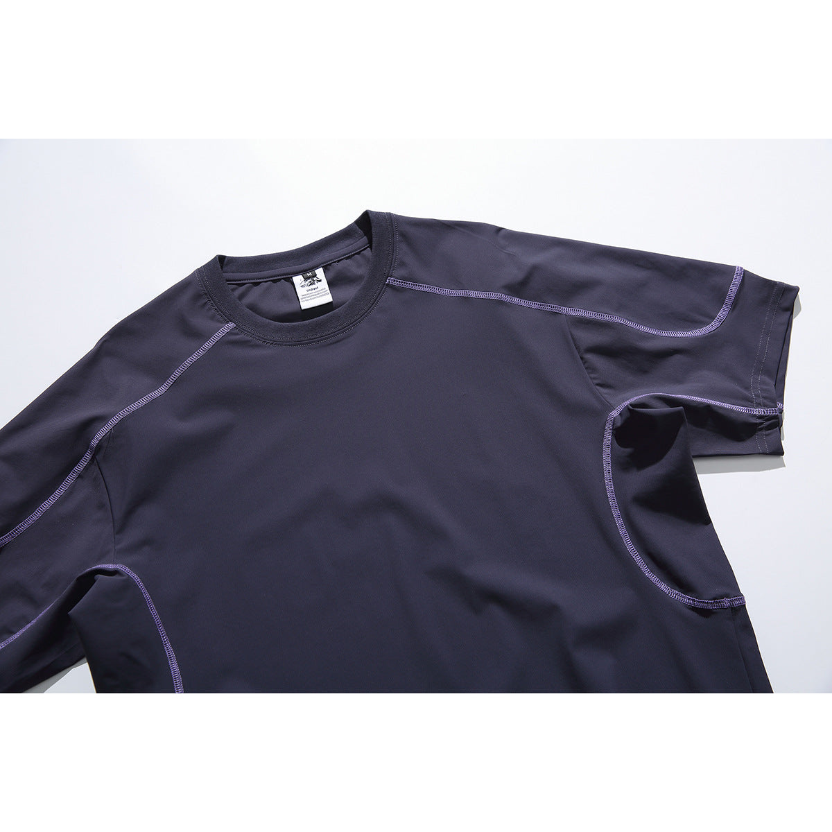 Close-up of a dark navy crew-neck shirt with short sleeves and purple contrast stitching.