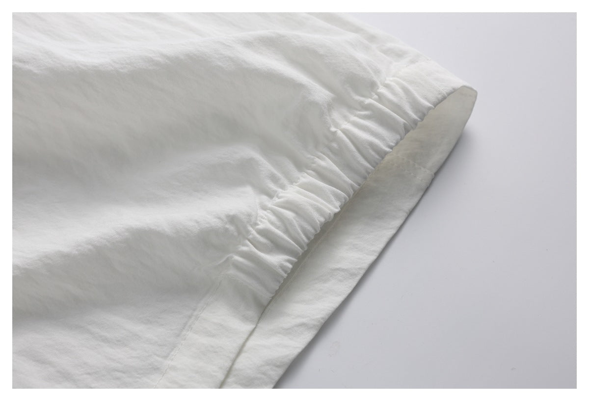 Close-up of a gathered elastic seam and folded stitched edge on the white garment.