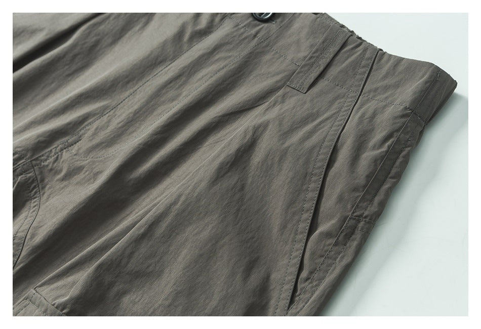 Close-up of charcoal-gray trousers showing a button, belt loop, and stitched seams.