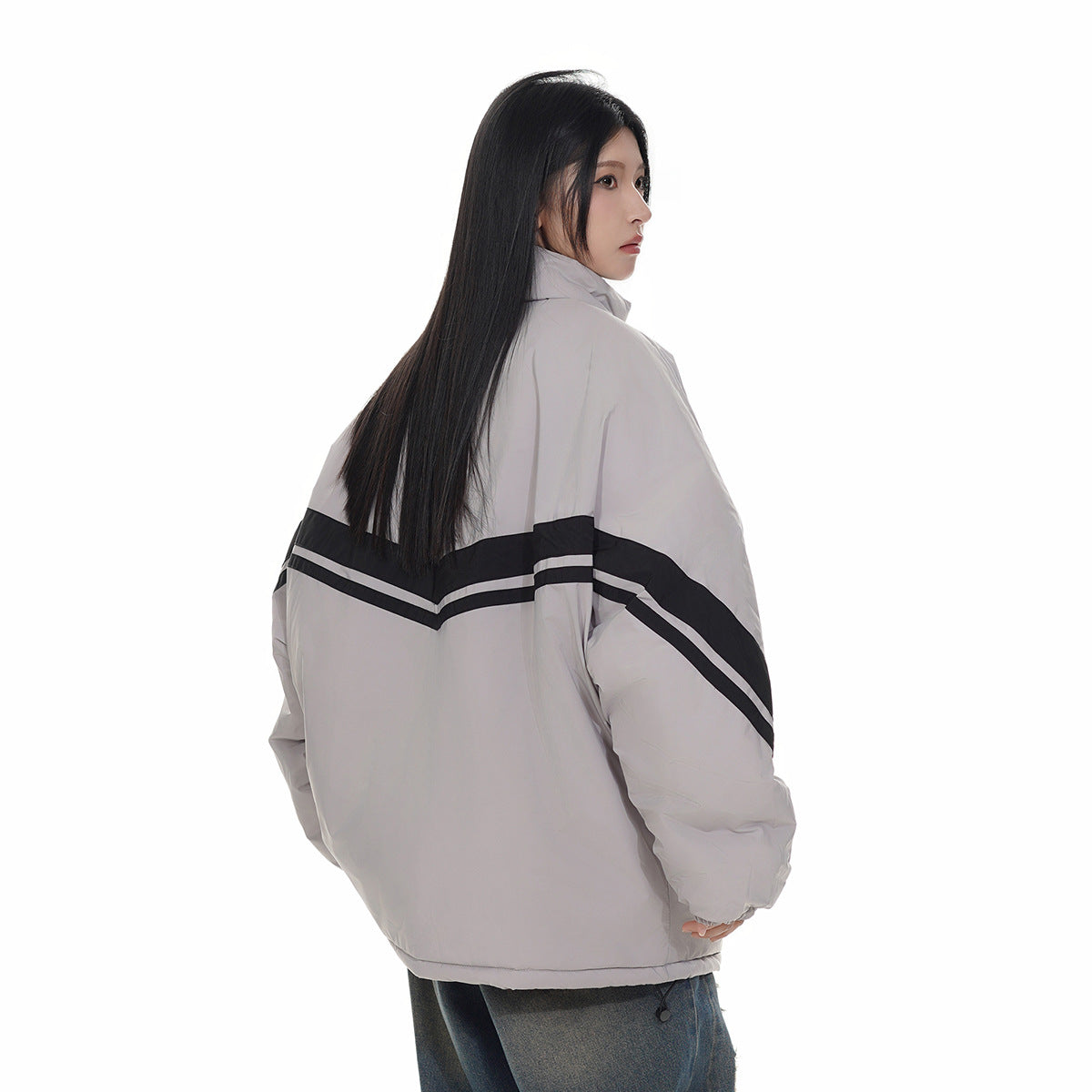 Model showing the back of a light gray oversized jacket with black and gray chevron stripes.