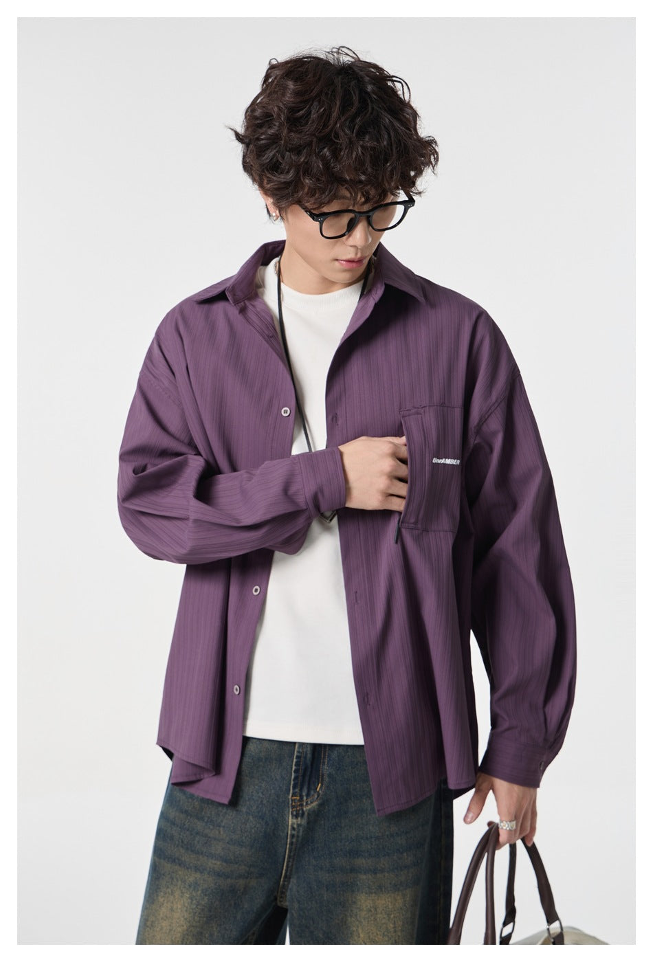 Close view of a model wearing a muted purple button-front shirt with a chest pocket over a white tee.