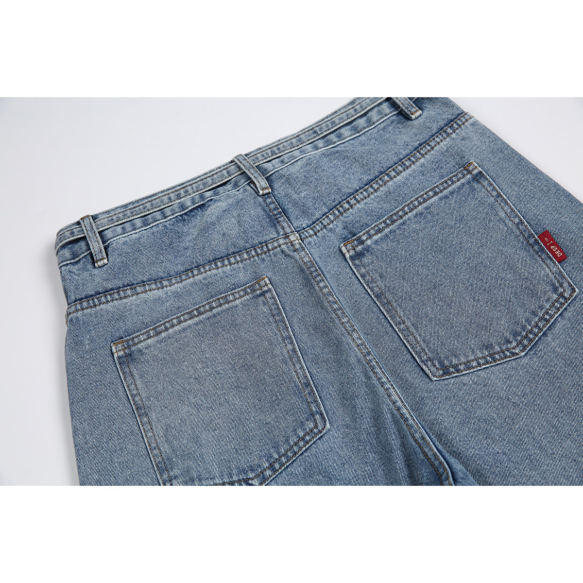 Close-up of light blue jeans showing the back waistband, yoke and two patch pockets.