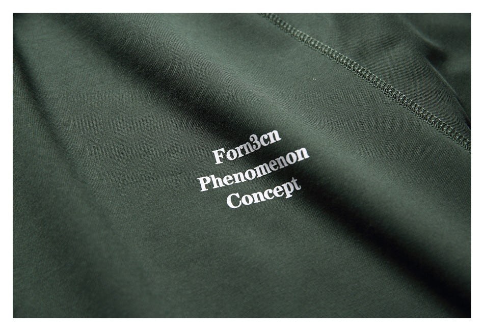 Close-up of white text reading “Forn3cn Phenomenon Concept” printed on the dark green shirt.