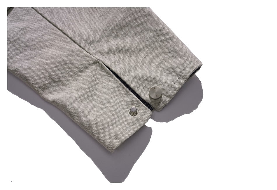 Close-up of a light gray jacket cuff with a metal snap button.