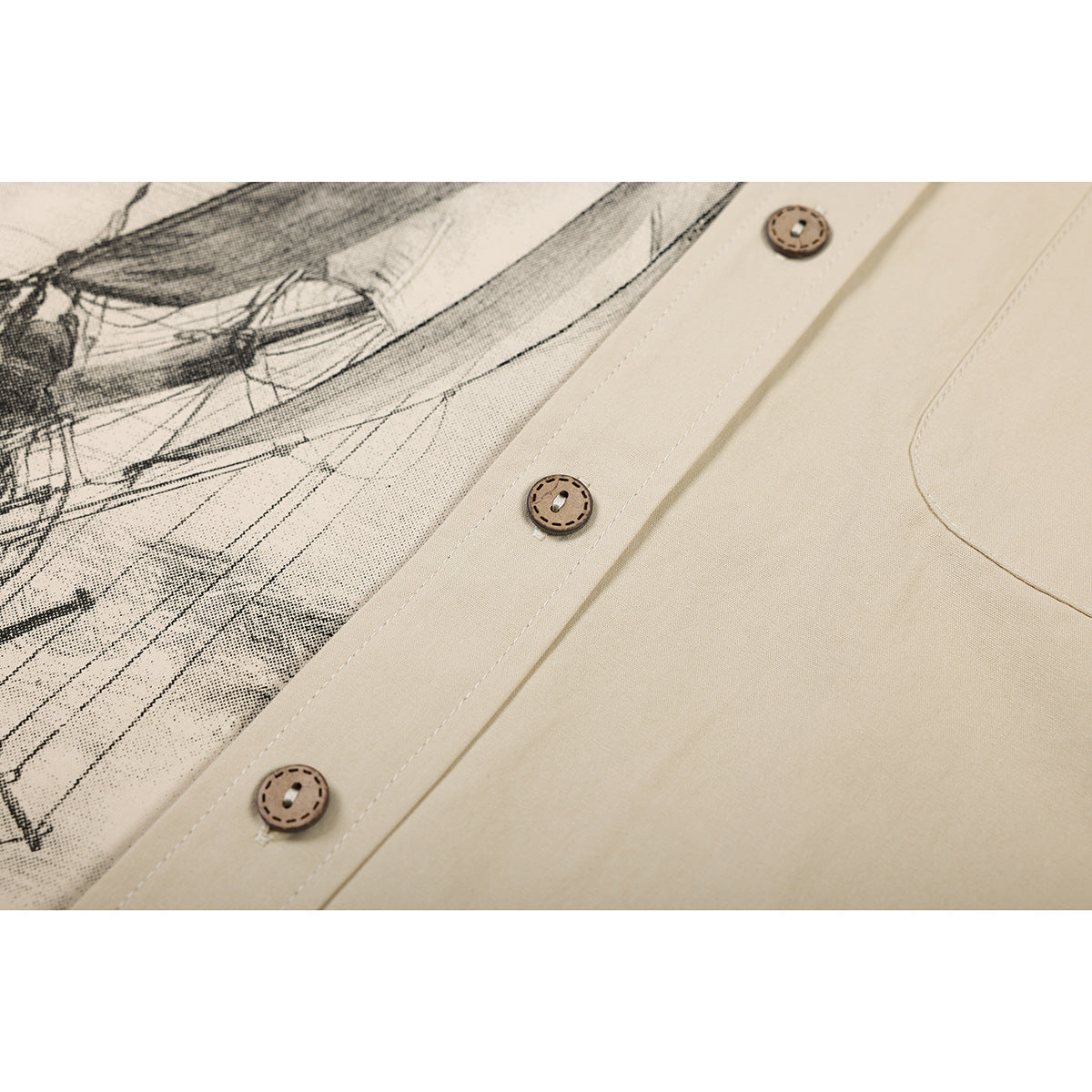 Close-up of a beige shirt with brown buttons and a black-and-beige sailing ship print.