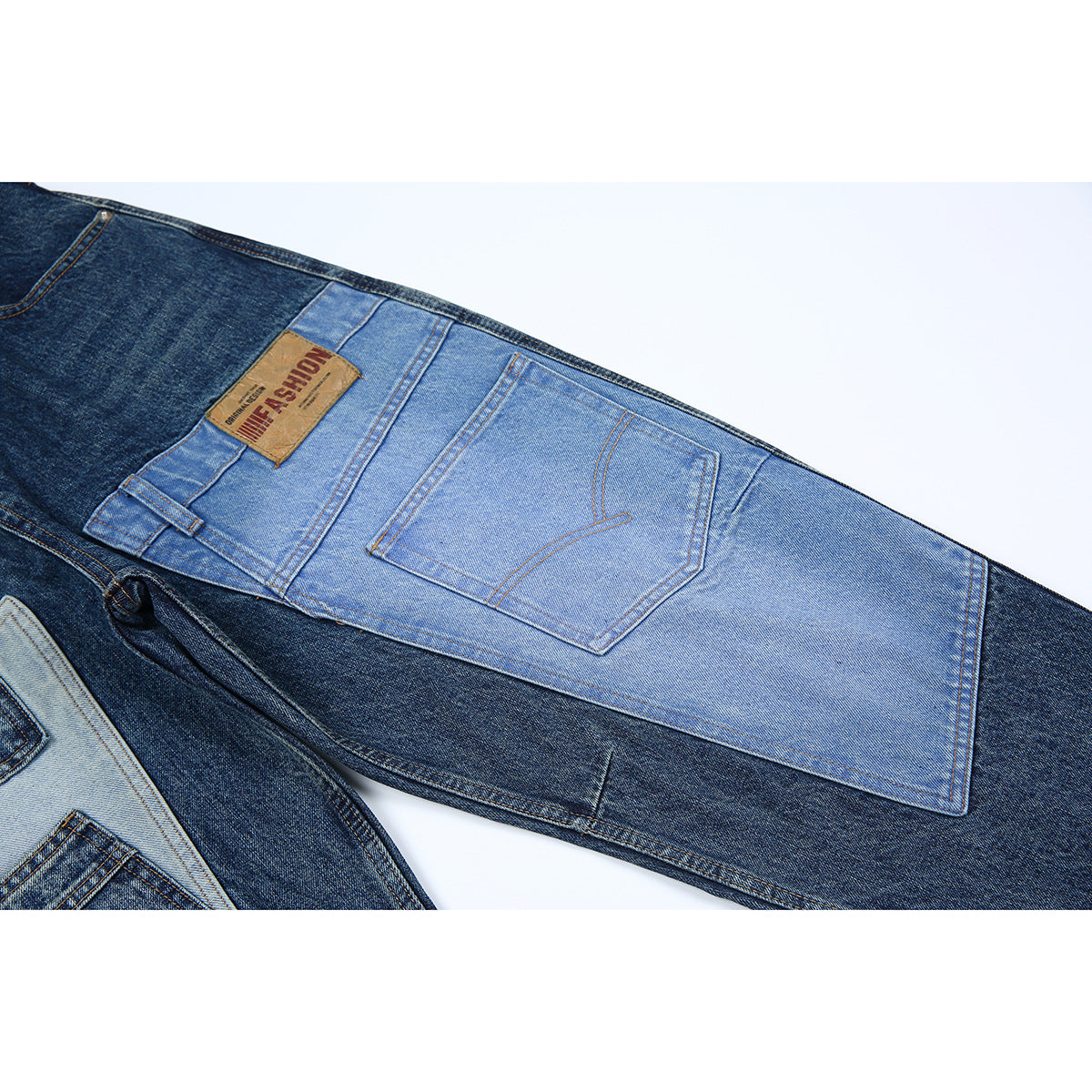 Close-up of jeans showing a light blue denim back-pocket panel, contrast stitching, and a tan waistband patch.