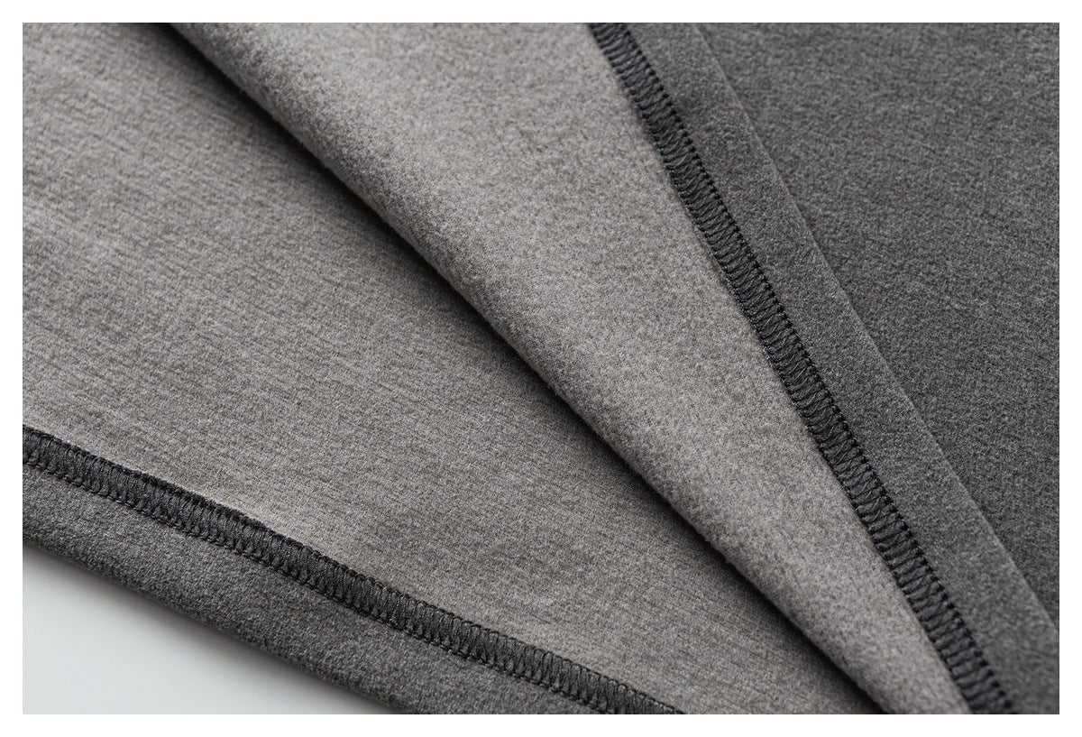 Close-up of the inside of gray fabric showing dark overlock seams and stitching.
