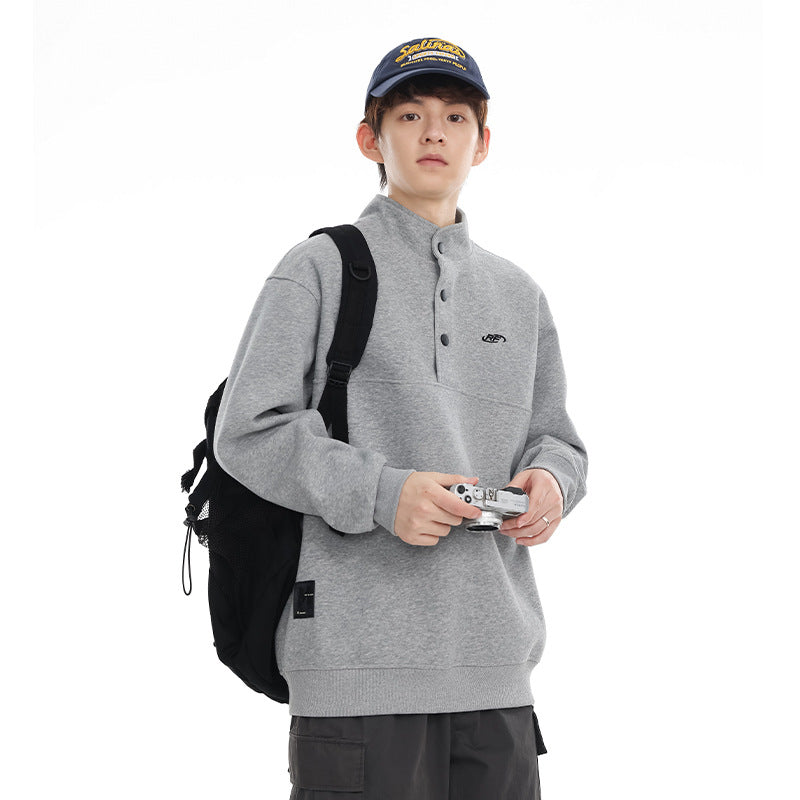 Model wearing a light gray pullover with a stand collar and buttons, shown from the front.
