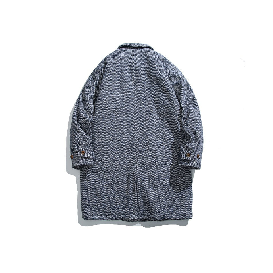 Back view of a dark gray herringbone coat laid flat, with a collar and buttoned sleeve tabs.