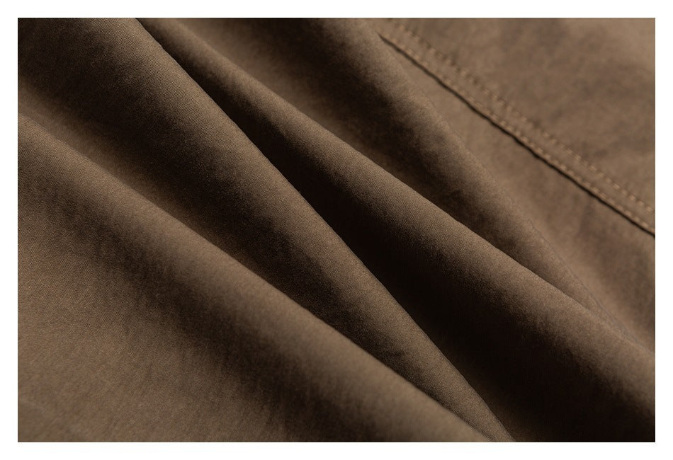 Macro view of brown trouser fabric folds and a stitched seam.
