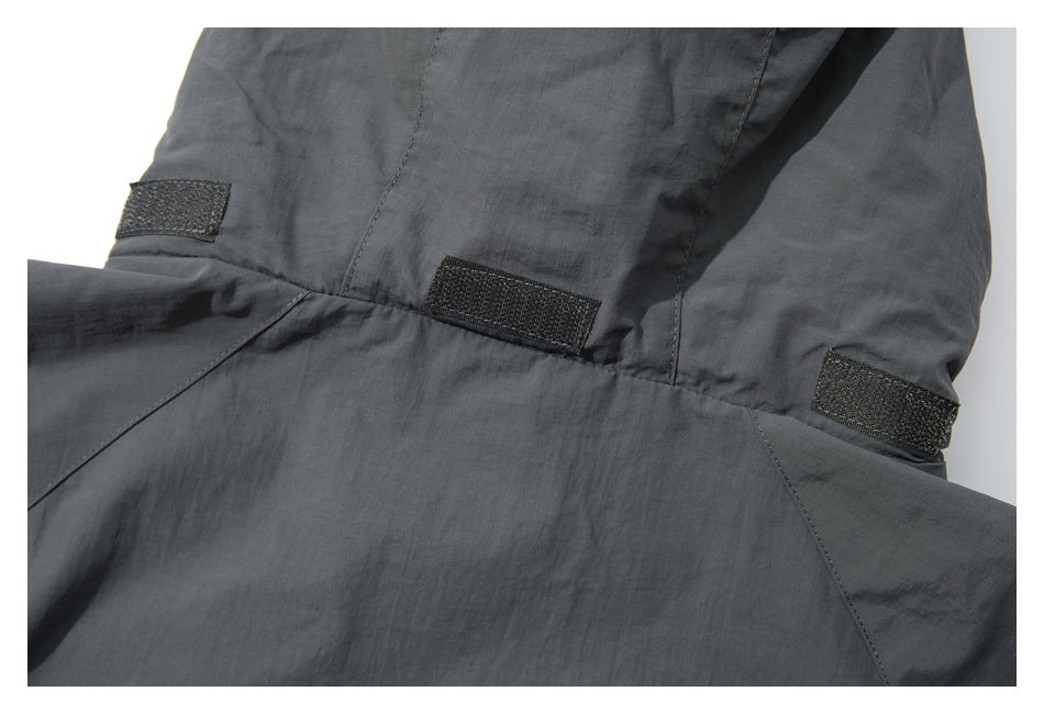 Close-up of a charcoal-gray jacket showing stitched panels and several black hook-and-loop tabs.
