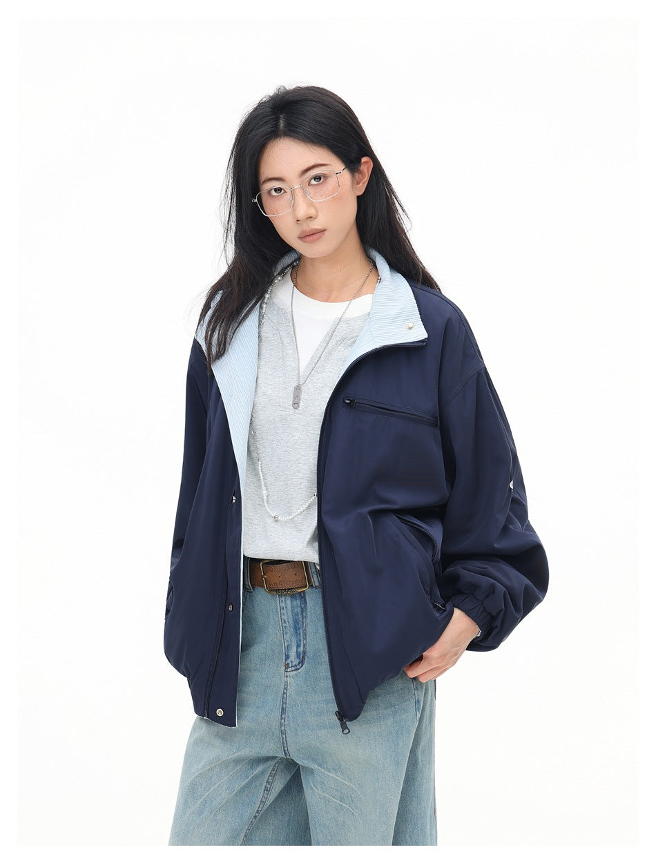 Angled view of a model wearing a navy jacket with a pale blue collar, zip chest pocket, and elastic cuffs.